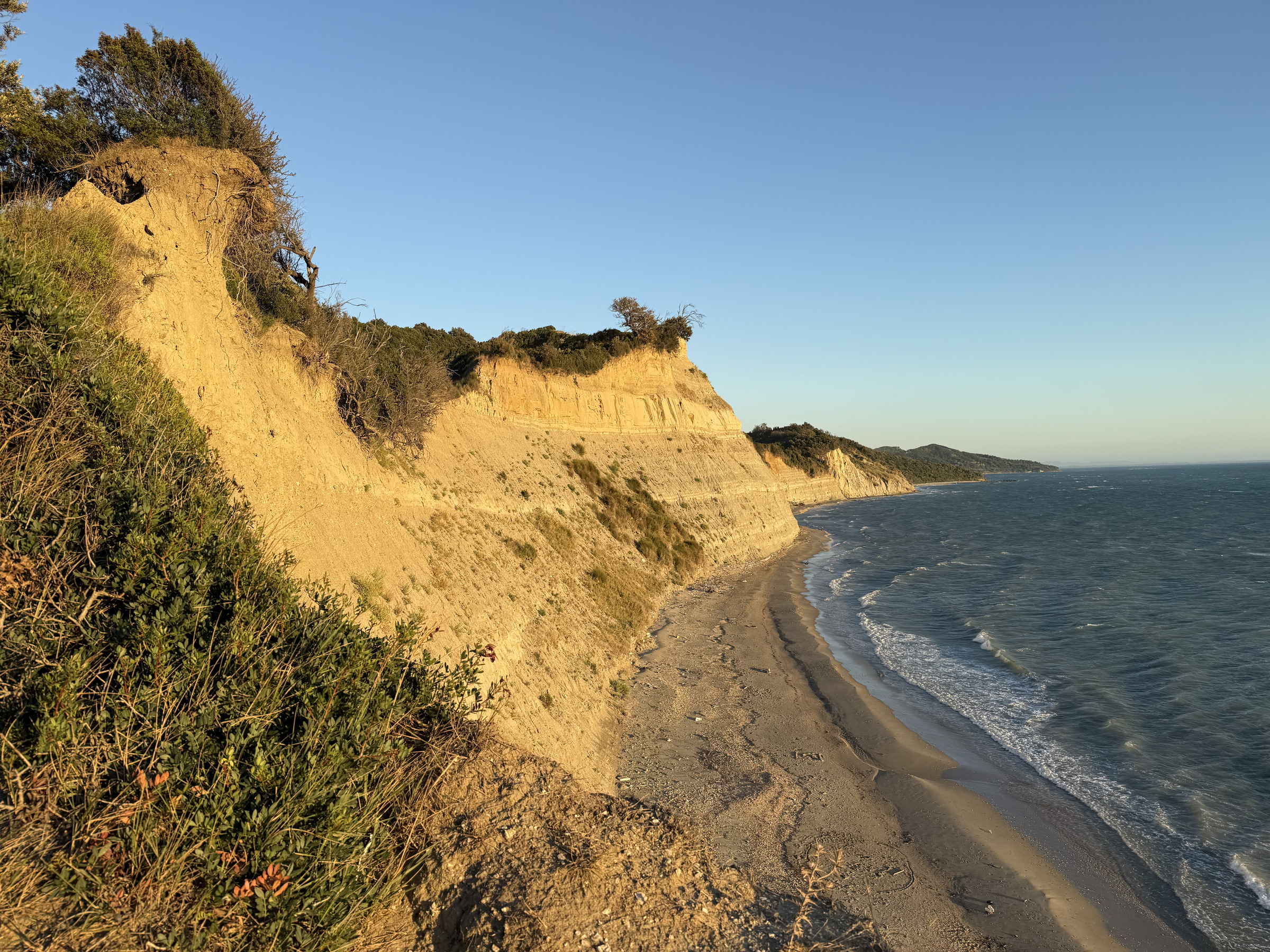 Sunlit cliffs and the sea at Cape Rodon.